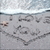 A beach scene with footprints in the sand forming a heart shape, waves crashing on shore, and small brown objects scattered near the water's edge.