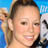 Pixelated static image of a person with light skin tone, dark hair tied back, and visible facial features including eyes, nose, mouth, and cheeks against a blue background.