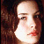Pixelated close-up of a person's face with light skin, dark brown hair, and red lips, set against a dark brown background.