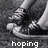 Black-and-white pixelated image of a person's lower legs and feet in sneakers, with text overlays reading 'hoping', 'dreaming', and 'wishing' across three sections.