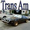 Pixelated blue text 'Trans Am' above a blurry image of a dark-colored car with gold wheels on a street.