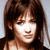 Static pixelated image of a woman with brown hair and light skin, cropped to show upper shoulders and face against a plain background.