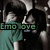 Two side-by-side pixelated figures in dark clothing with teal accents, one holding a small object near their face, green text reading 'Emo Love' below.
