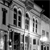 Black-and-white pixelated image of a building facade with multiple windows and architectural details, viewed from a low angle.