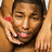 A person with dark hair and light skin holds their hands near their face, wearing a red wristband on the left wrist.