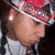Pixelated close-up of a person wearing a red and white striped hat with dark brim, light-colored shirt, and visible ear.