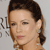 A pixelated close-up of a person with dark brown hair styled in an updo, wearing a light-colored garment with visible shoulder details.