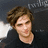 Pixelated close-up of a person with brown hair wearing a dark shirt against a dark background with light patches.
