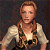 A pixelated image of a person with long braided hair wearing a white blouse and patterned vest against a dark background, next to green text reading "Original Icons .com" on a solid green field.