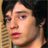 Static 48x48 pixel icon showing a close-up of a person's face with dark hair, red lips, and visible facial features against a dark background with light-colored vertical stripes on the left.