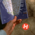 A pixelated image shows a hand reaching toward a red circular object with white text, set against a blurred background of blue and brown tones.