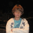 Pixelated static image of a person with short brown hair wearing a light-colored shirt over a blue undershirt against dark background.