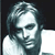Pixelated grayscale portrait of a person with shoulder-length hair, wearing a light-colored shirt against a dark background.