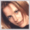 Pixelated image of a person with light brown hair and blue eyes, wearing a black sleeveless top with a silver butterfly design on the chest.
