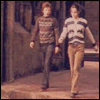 Two young men walk side-by-side in a stone corridor, then one changes into a black shirt while text about cats and rats appears sequentially.