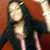 A person with long dark hair and a black top over pink clothing poses against a reddish-brown background, showing slight variations in head position across frames.