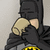 Batman character in black cowl and cape holding a beige mug, with yellow-and-black chest emblem visible.