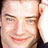 Pixelated close-up of a person's face with visible eyes, nose, mouth, and hair in warm tones on a light background.