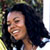 Static 50x50 pixel buddy icon showing a smiling person with dark curly hair in profile view against a blurred background.