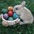 A white rabbit sits beside a basket of colorful Easter eggs on green grass, with text overlays expressing admiration and holiday greetings.