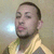 Pixelated portrait of a person with short dark hair, light skin, and a yellow shirt against a muted background with a bright light spot.