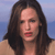 A pixelated close-up of a person with long dark brown hair, light skin, and red lips against a blue gradient background.