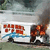 Animated sequence showing a white van with blue wave patterns and red text, first intact then on fire.