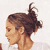 Pixelated static image of a person's profile with brown hair tied up, light skin tone, and visible ear against white background.