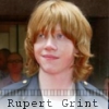 Static image of a person with light brown curly hair wearing a dark jacket over a white shirt, with text below reading 'Rupert Grint'.