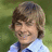 A pixelated image split into two sections: a person with light brown hair and a light blue shirt on the left, and yellow text on a green background on the right.