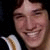 Two side-by-side pixelated frames of a person smiling, one with dark hair and the other wearing a dark beanie hat.