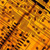 A pixelated static image with a dominant orange and brown color palette, featuring scattered dark brown and black pixels against a textured background.