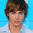 Pixelated close-up of a person with brown hair against a bright blue background, wearing a light-colored shirt.