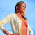 A pixelated image of a woman in a white cardigan over an orange top, standing with hands on hips against a blue sky background.