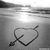Static grayscale icon featuring a heart pierced by an arrow on a gradient background with light reflection.