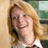 Pixelated image of a person with light brown hair and a white-collared shirt, overlaid with red pixelated text on black background.