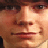 Static close-up of a person's face with pixelated rendering and warm color tones, likely from an older digital image or low-resolution source.