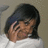 Pixelated image of a person with dark hair wearing a white top, hand raised near face, against a neutral background.