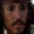 Pixelated close-up of a person with dark hair, mustache, and beard, wearing a dark hat and light-colored shirt, against a dark background.