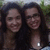 Two people with long dark hair smiling closely together in a pixelated outdoor setting with green foliage background.