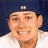 A person wearing a dark blue cap with white text and a white shirt, smiling in three showing slight head movement