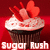 Pixelated cupcake with white frosting, red sprinkles, and heart-shaped decorations on a red background.