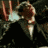 Animated sequence of a person in formal attire with repeated hand gestures and shifting facial expressions against a dark background.