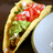 Pixelated taco image with visible fillings on a light blue plate, accompanied by the word 'taco' in pixelated text.
