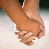 Two hands clasped together in a close-up view, with one hand holding the other's wrist; a small pink heart appears and disappears between them.