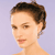 Pixelated close-up of a person's face with short brown hair, light skin, and a neutral expression against a light purple background.