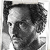 Black-and-white pixelated portrait of a person with short dark hair, visible ear, and partial facial features including eye and nose, cropped to show upper head and shoulders.