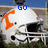 Two identical white football helmets with orange accents and black face masks, positioned side-by-side on a grassy field under blue sky.