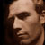 Static pixelated close-up of a person's face with visible facial features and neutral expression on dark background.