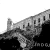 A grayscale pixelated image shows a partial view of a building with a sloped roof and multiple windows, set against a white background with dark lower sections.